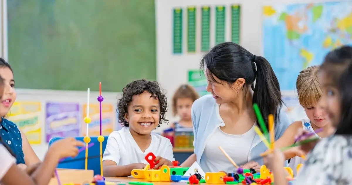 Crianças de 3 anos participando de atividade lúdica em sala de aula, com apoio visual e materiais pedagógicos coloridos.