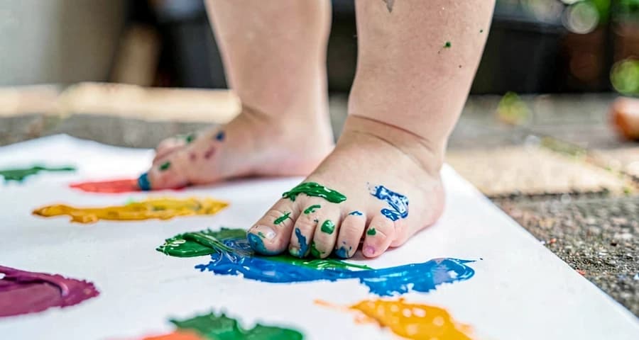 pé de criança coberto de tinta durante atividade artística corporal na creche