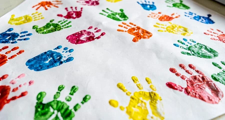 papel com marcas coloridas de mãos e pés feitas por crianças na creche