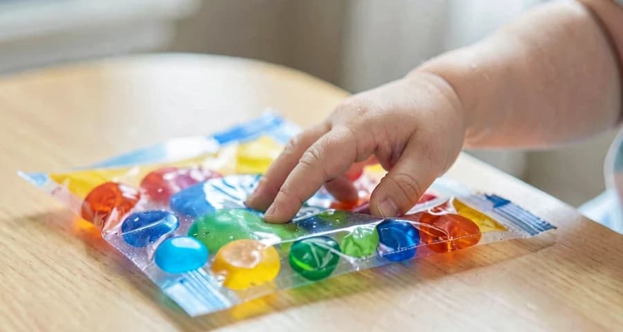 dedo de bebê pressionando saco sensorial colorido em atividade na creche