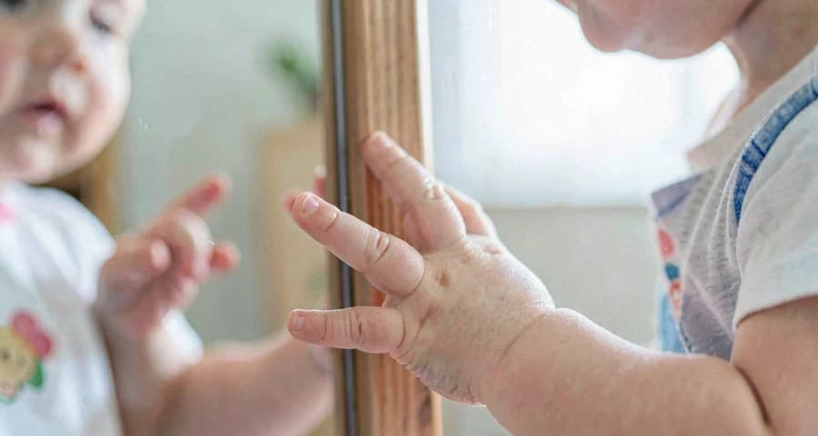 mão de bebê tocando espelho durante atividade de autopercepção na creche