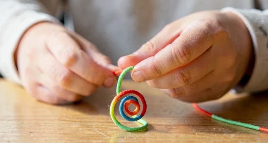 criança da creche moldando arame colorido em forma de espiral