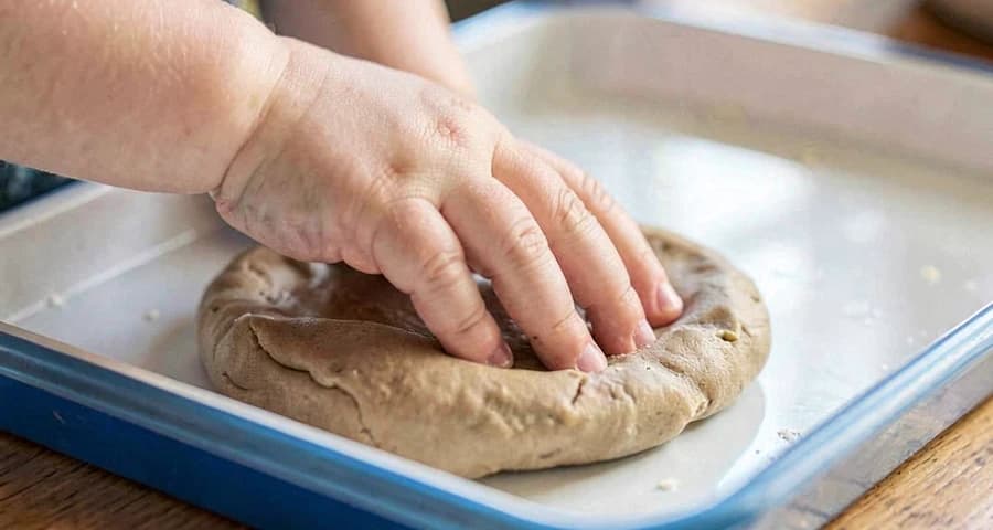 bebê apertando massinha caseira macia durante atividade sensorial na creche
