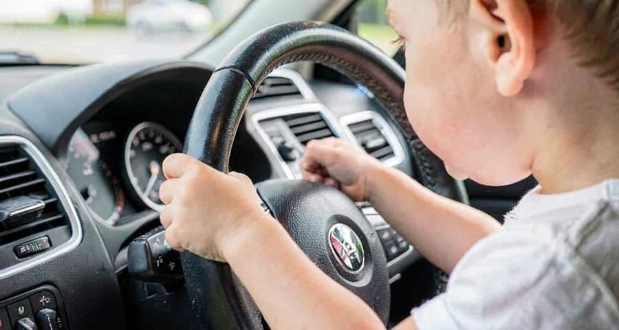 criança da creche imitando gesto de motorista durante atividade de profissões