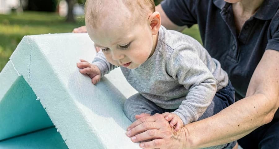 bebê subindo rampa macia com apoio de educadora na creche