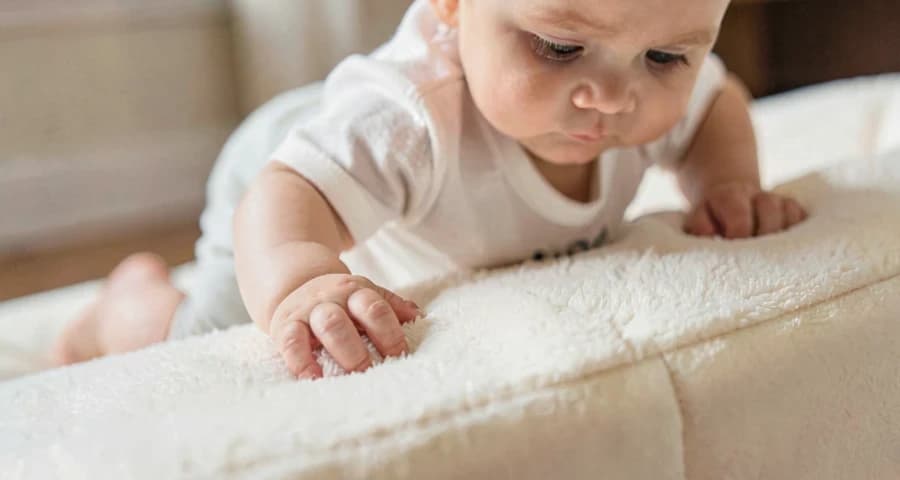 bebê subindo sobre elevação macia de almofadas com apoio na creche