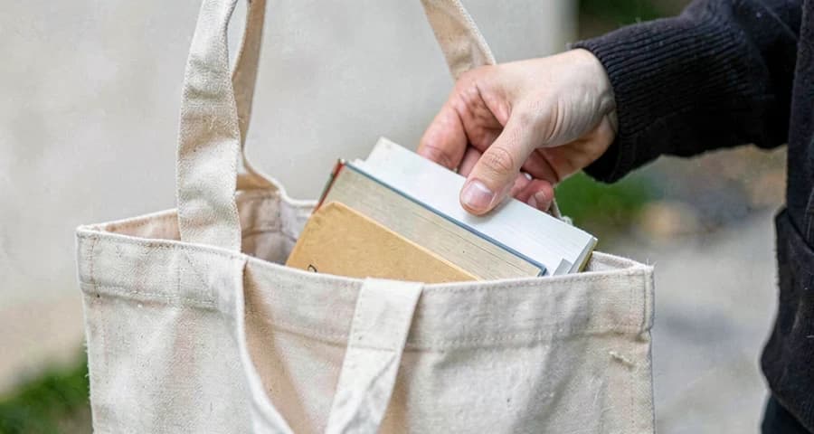 criança da creche guardando livro emprestado na sacola