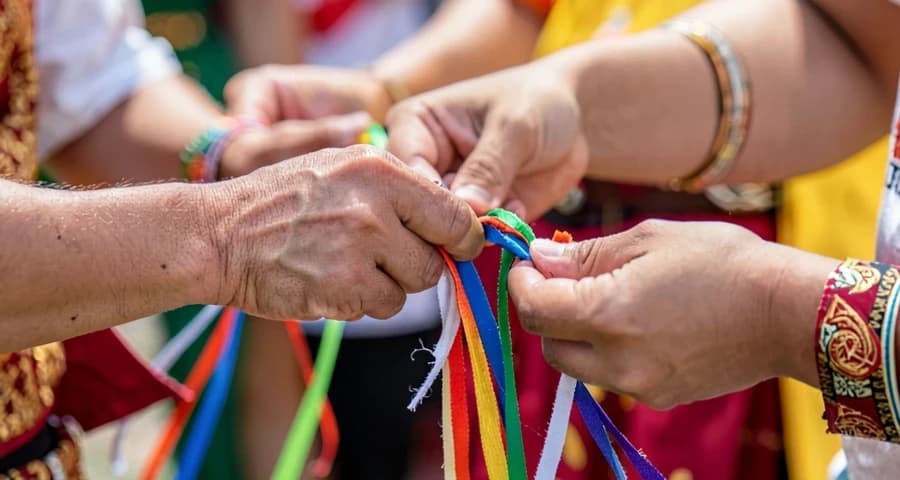 mãos de criança segurando fitas coloridas durante dança tradicional na creche